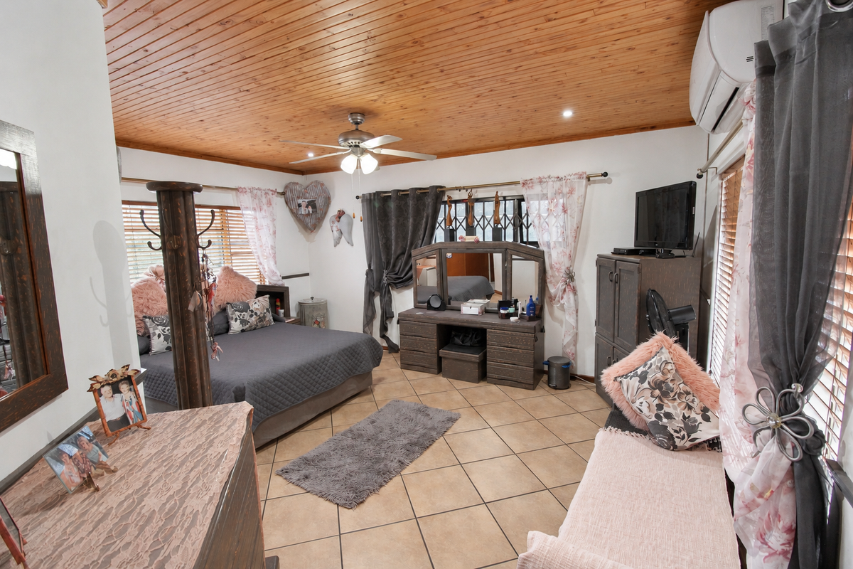 Spacious bedroom featuring a warm timber-clad ceiling, tiled flooring, and a wall-mounted air conditioning unit.