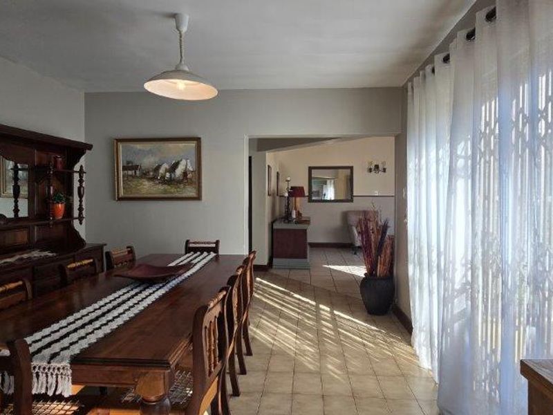 A dining room featuring tiled flooring and large sliding glass doors with security gates, providing natural light and access to the exterior.