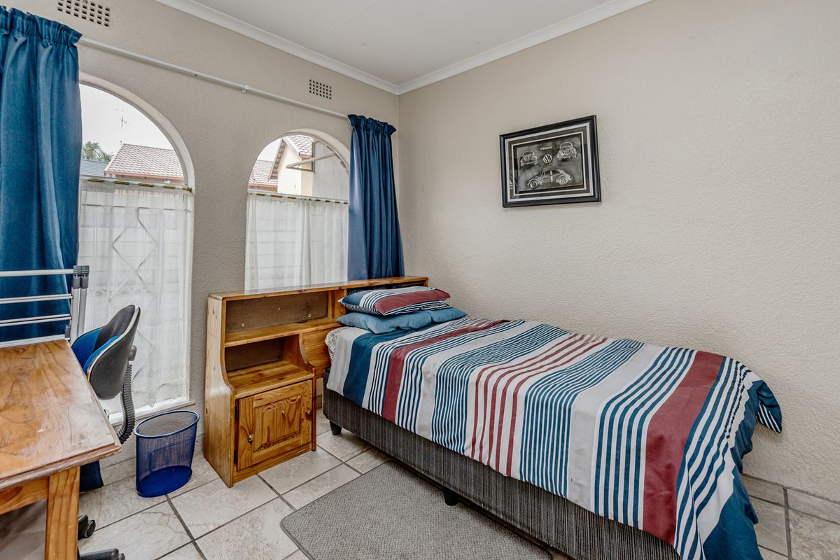 A bedroom featuring arched windows, tiled flooring, and neutral wall finishes, providing a functional space with natural light.