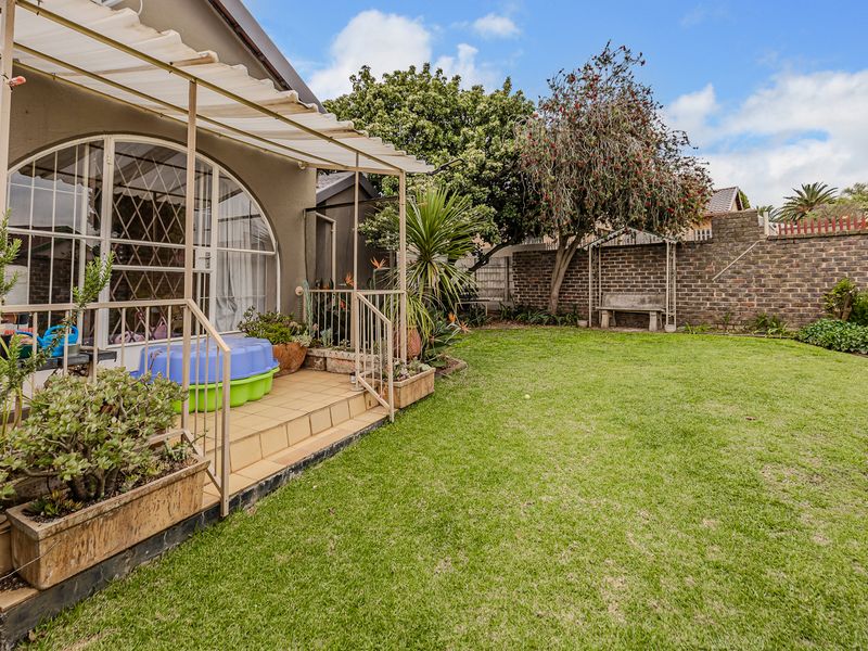 A private rear garden featuring a covered patio area, established lawn, and secure brick boundary walls, offering a peaceful outdoor space.