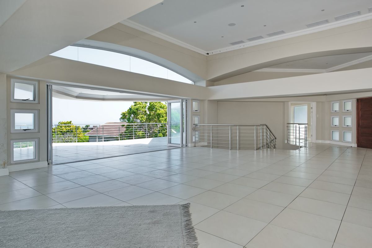 Spacious open-plan living area featuring large stacking doors leading to a balcony, tiled floors, and modern stainless steel balustrades.
