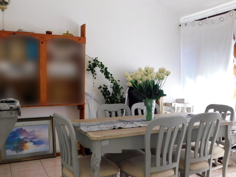 A bright dining area featuring tiled flooring and direct access to the outdoors through a sliding glass door.