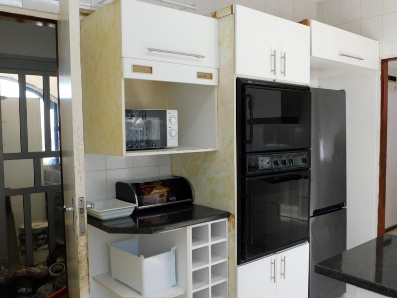 Kitchen area featuring built-in oven, microwave, and granite countertops, requiring cosmetic updates to cabinetry and wall finishes.