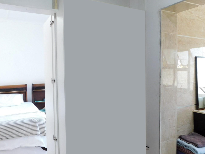 A bedroom area featuring an adjacent open-plan vanity space with tiled walls, showing signs of incomplete finishing and construction work.