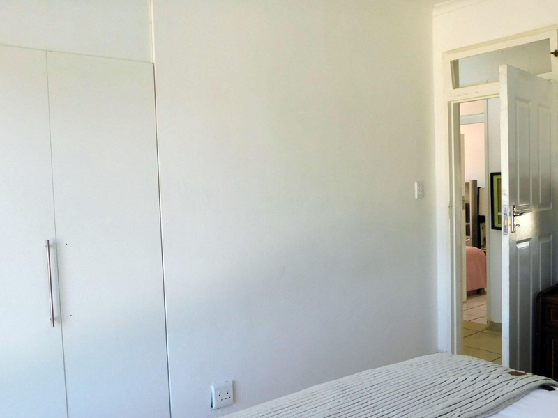 A bedroom featuring a built-in wardrobe and a doorway leading to an adjacent room with a transom window above.