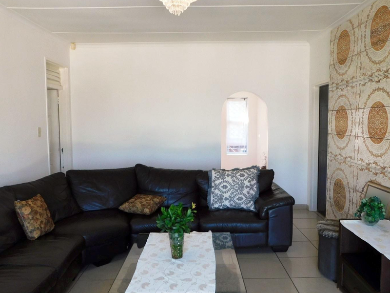 A living room featuring tiled flooring, an arched doorway, and a decorative tiled feature wall.