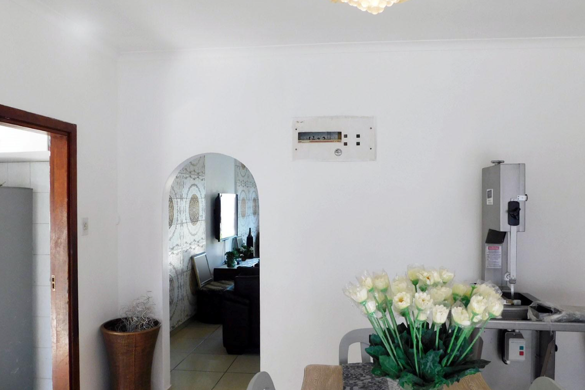 A living area featuring a classic archway leading to an adjacent room and a wall-mounted electrical distribution board.