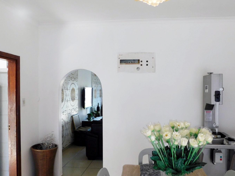 A living area featuring a classic archway leading to an adjacent room and a wall-mounted electrical distribution board.