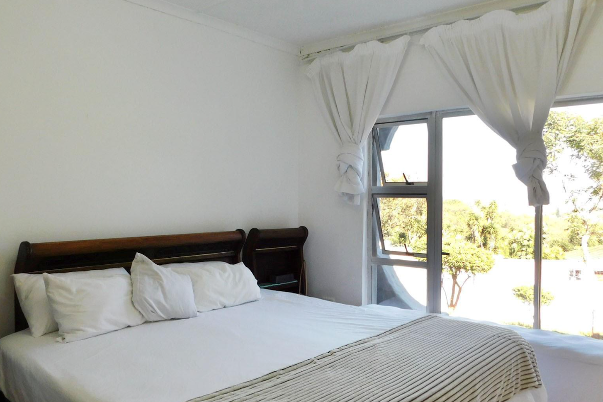 A bright bedroom featuring a sliding glass door that provides natural light and access to the outdoor area.
