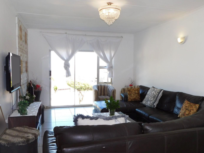 A living room featuring tiled flooring, decorative wall accents, a crystal chandelier, and a sliding glass door providing access to the exterior.