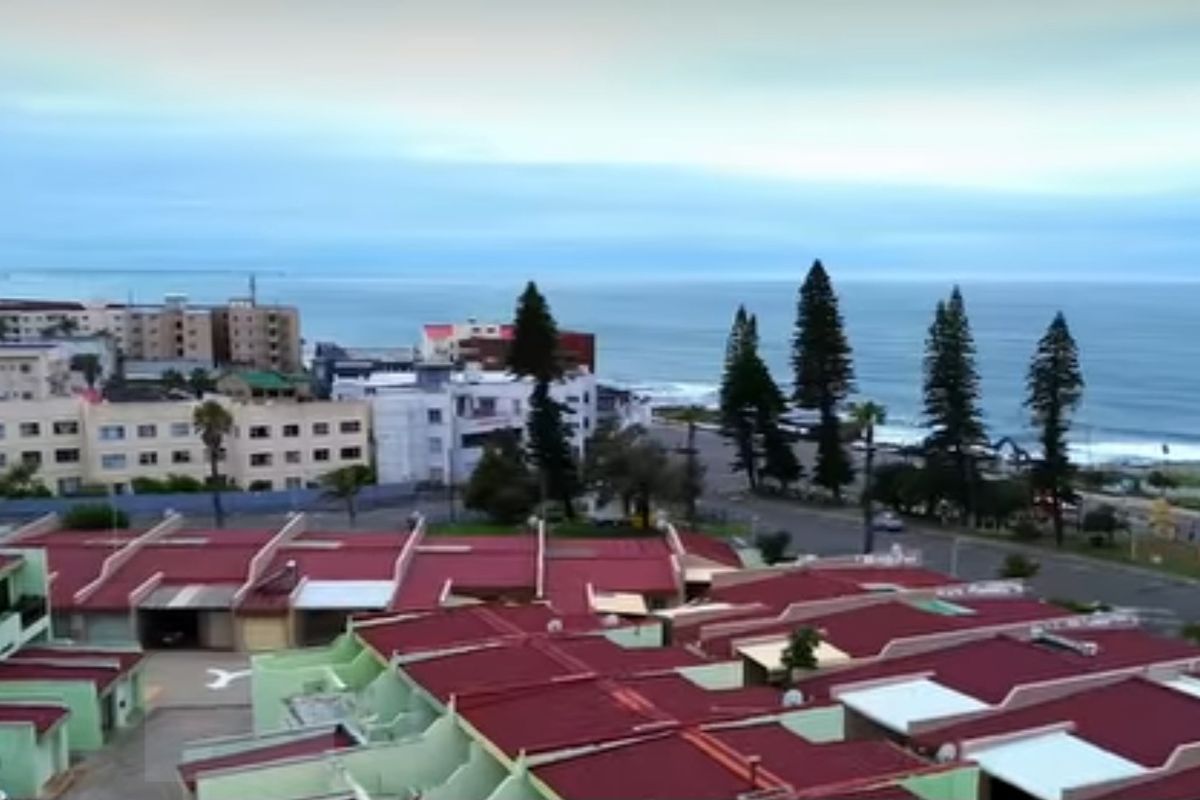 An elevated aerial view showing the townhouse complex rooftops with a scenic coastal and ocean backdrop.