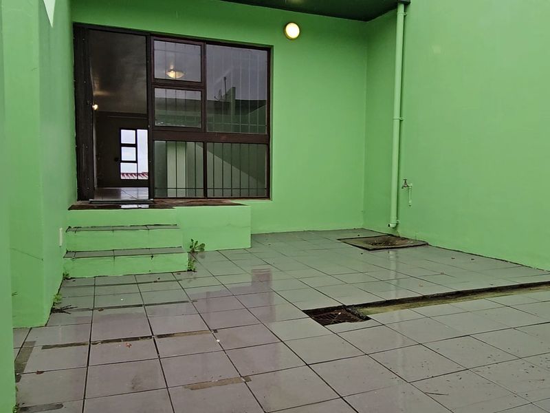 A paved outdoor patio area featuring tiled flooring, an external water tap, and direct access to the interior through a sliding glass door.
