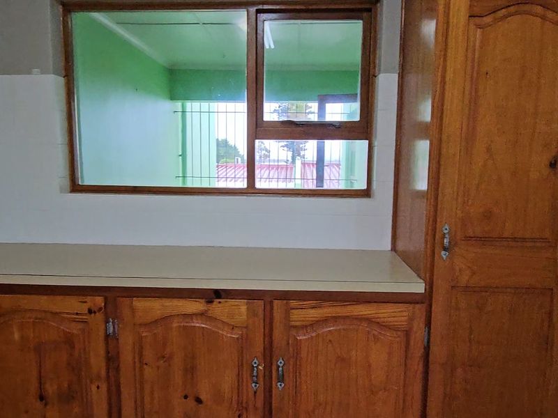 A dated kitchen area featuring wooden cabinetry, laminate countertops, and a tiled backsplash, offering a blank canvas for potential modern renovation.