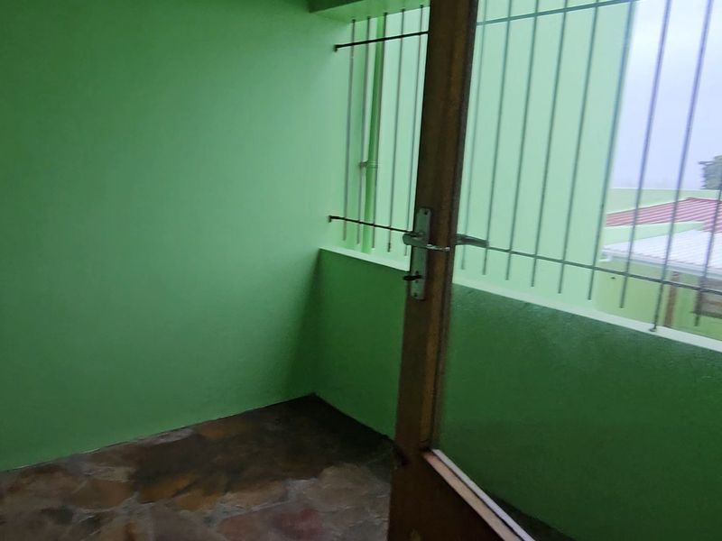 A covered balcony area featuring stone flooring and security bars, providing an outdoor space with potential for enhancement.