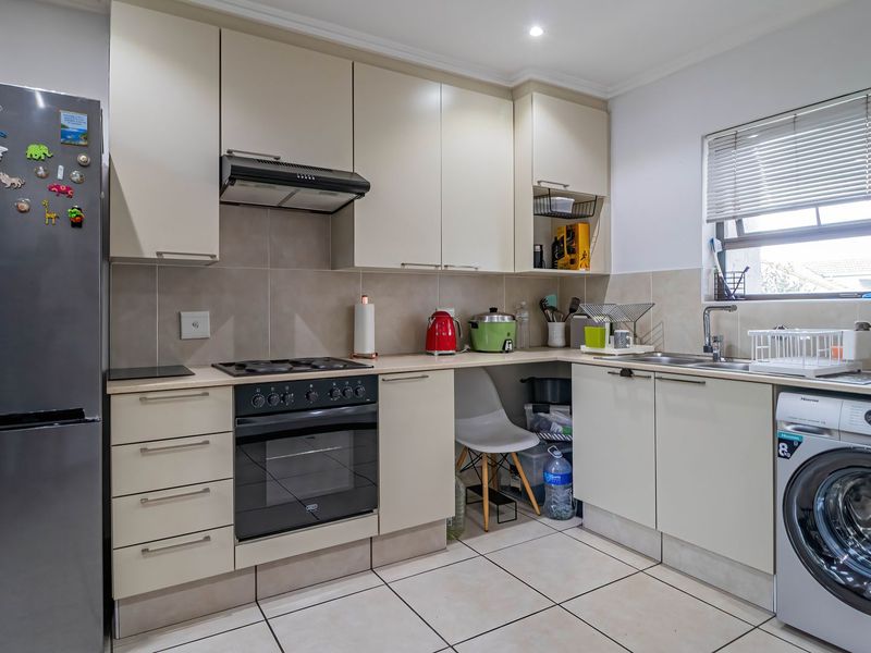 A functional kitchen featuring neutral cabinetry, tiled backsplash, built-in oven with hob, extractor fan, and integrated space for laundry appliances.