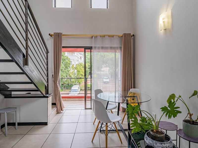Open plan living area featuring a modern staircase with metal balustrade, tiled flooring, and a sliding glass door leading to a balcony.