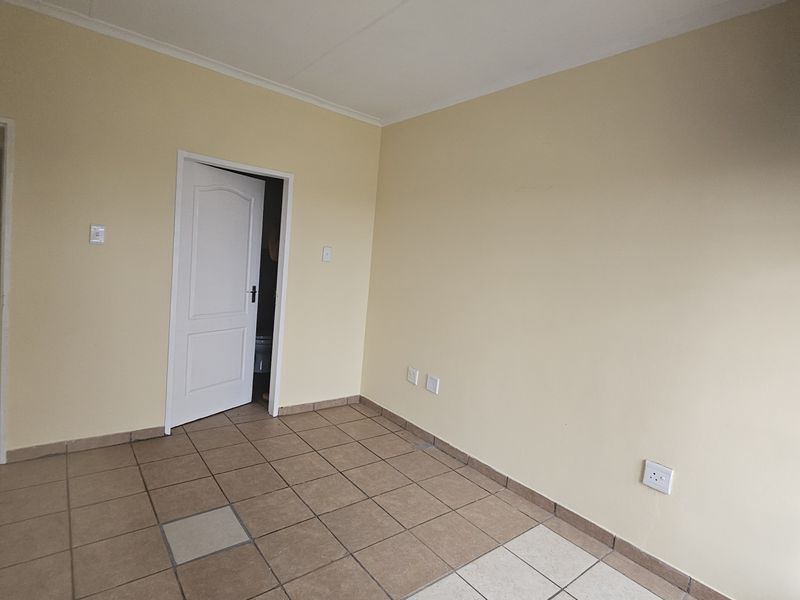 An empty bedroom featuring tiled flooring and neutral wall paint, providing a blank canvas for personalization.