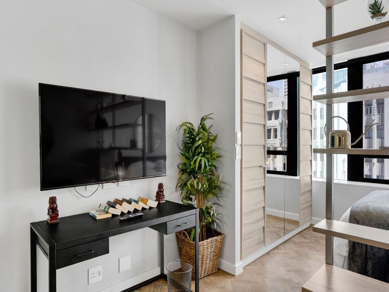 Modern bedroom featuring herringbone timber flooring, built-in mirrored wardrobes, and recessed ceiling lighting, offering a clean and contemporary aesthetic.