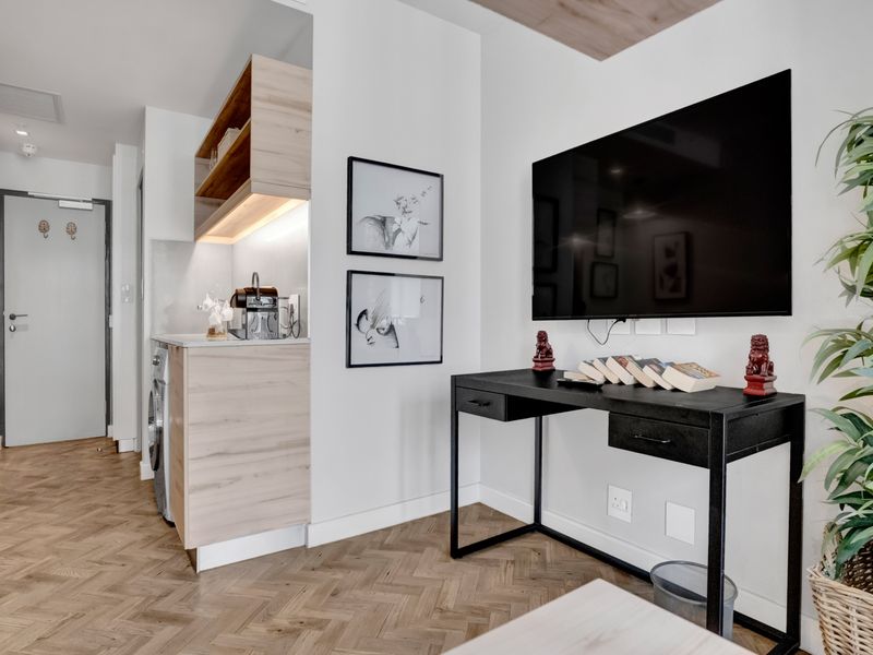 Modern open-plan living area featuring high-quality herringbone timber flooring, sleek built-in cabinetry with integrated appliances, and clean contemporary finishes throughout.