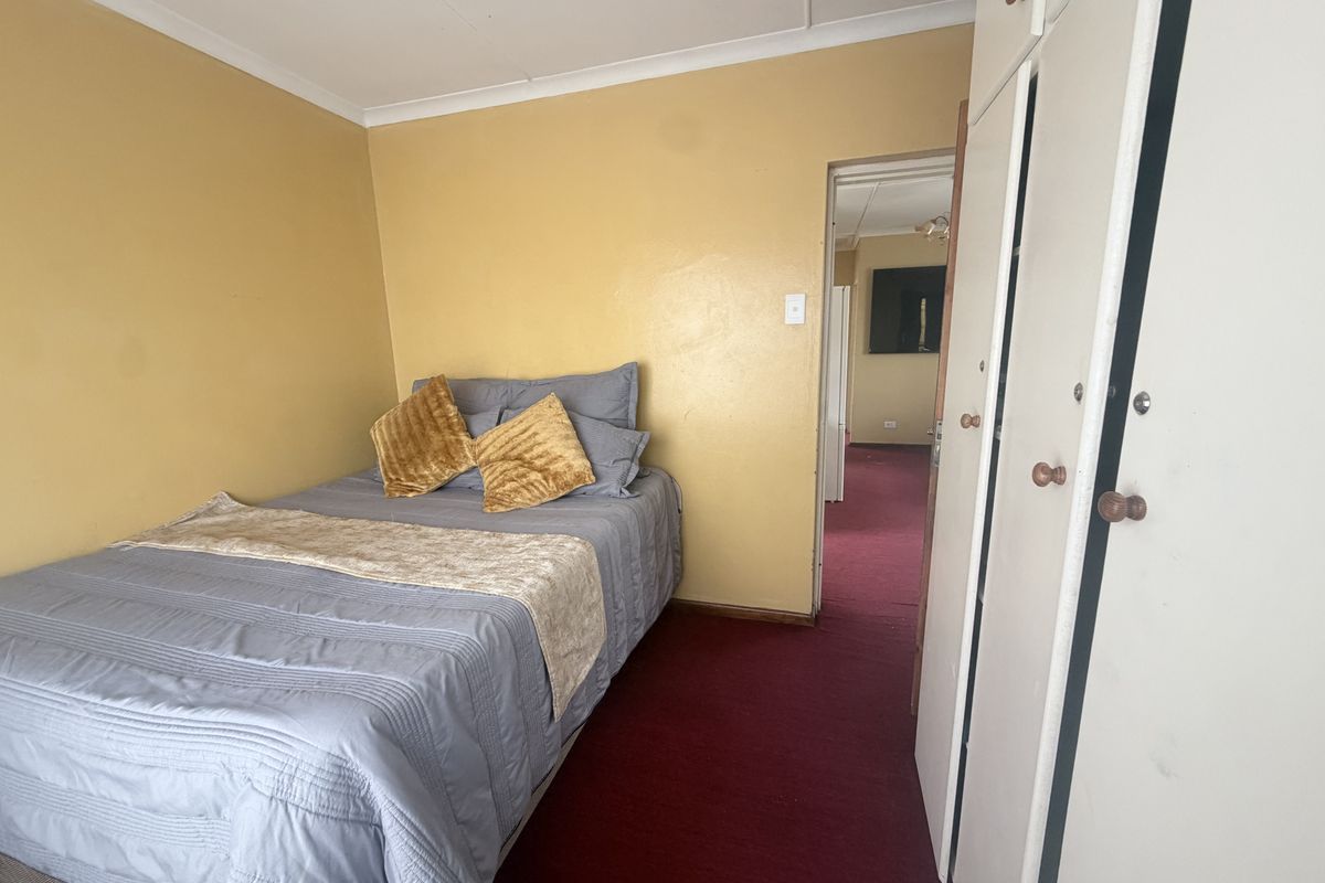 A bedroom featuring built-in cupboards, carpeted flooring, and coved ceilings, offering a functional space in need of cosmetic updates.