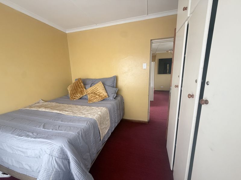 A bedroom featuring built-in cupboards, carpeted flooring, and coved ceilings, offering a functional space in need of cosmetic updates.