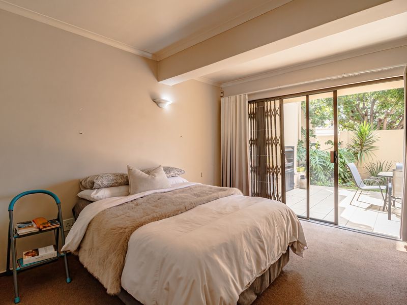 A bedroom featuring carpeted flooring, a wall-mounted light, and a sliding glass door providing direct access to a private patio area.