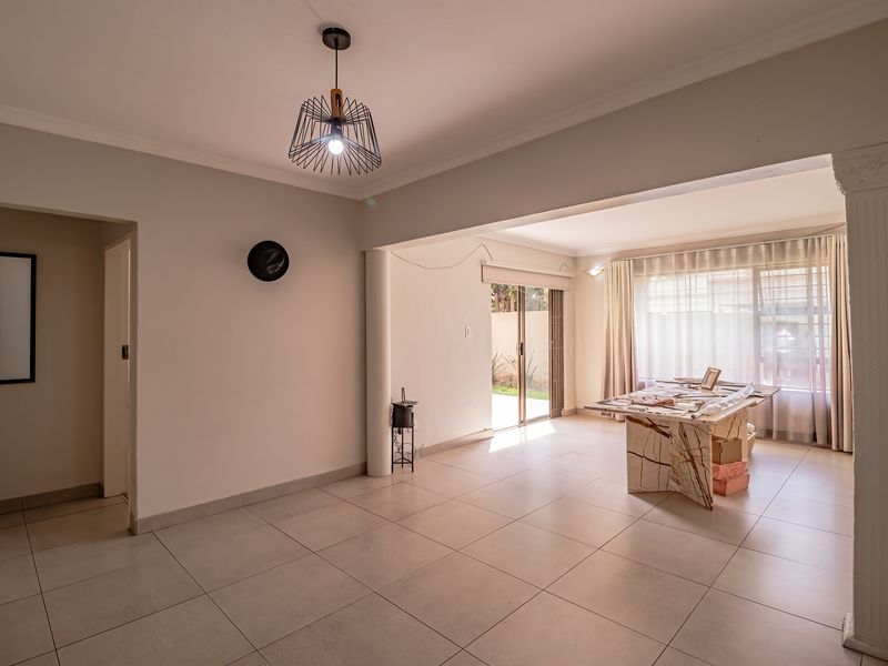 Spacious open-plan living area featuring large format floor tiles, a decorative column, and sliding glass doors providing access to the outdoor space.