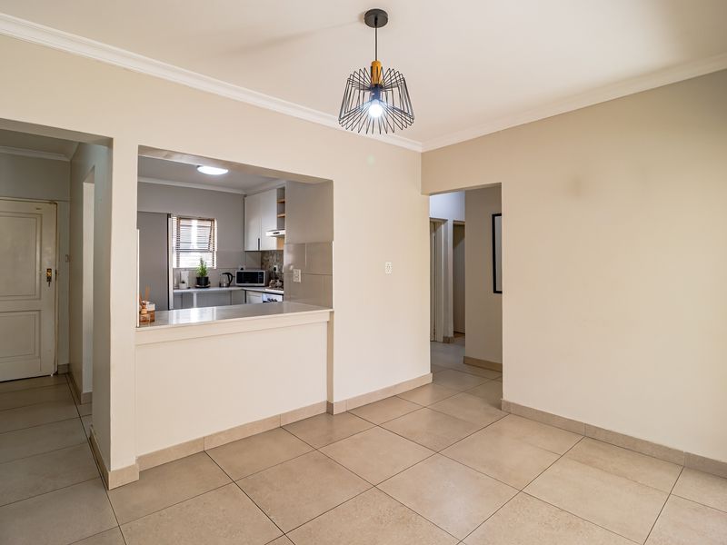 Open plan living area featuring tiled flooring, a breakfast counter, and a view into the adjacent kitchen space.