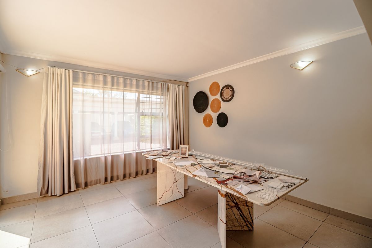 A bright and spacious living area featuring neutral tiled flooring, cove cornicing, and wall-mounted lighting, offering a clean canvas for interior design.