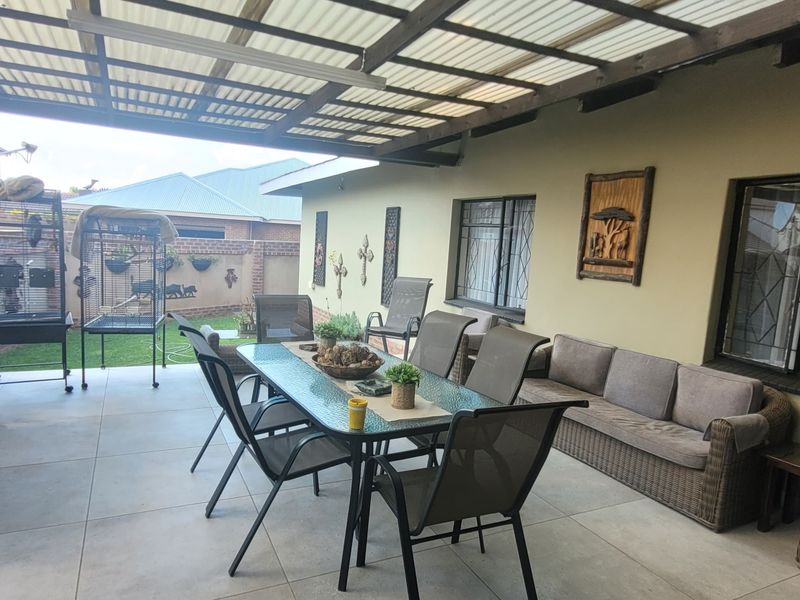 A spacious covered patio featuring tiled flooring, a translucent roof, and security-fitted windows, providing a functional outdoor entertainment area.