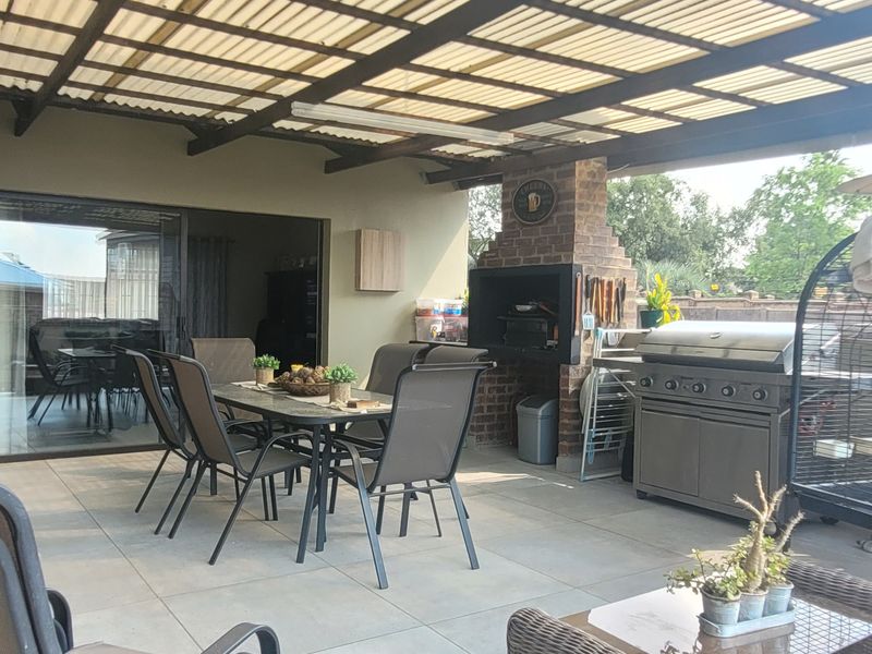 Covered outdoor patio featuring a built-in brick braai, tiled flooring, and direct access to the interior through sliding glass doors.