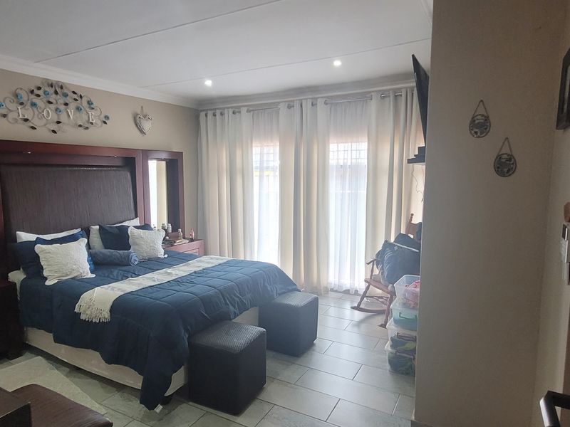 A spacious bedroom featuring tiled flooring, recessed ceiling lights, and a sliding glass door providing natural light.
