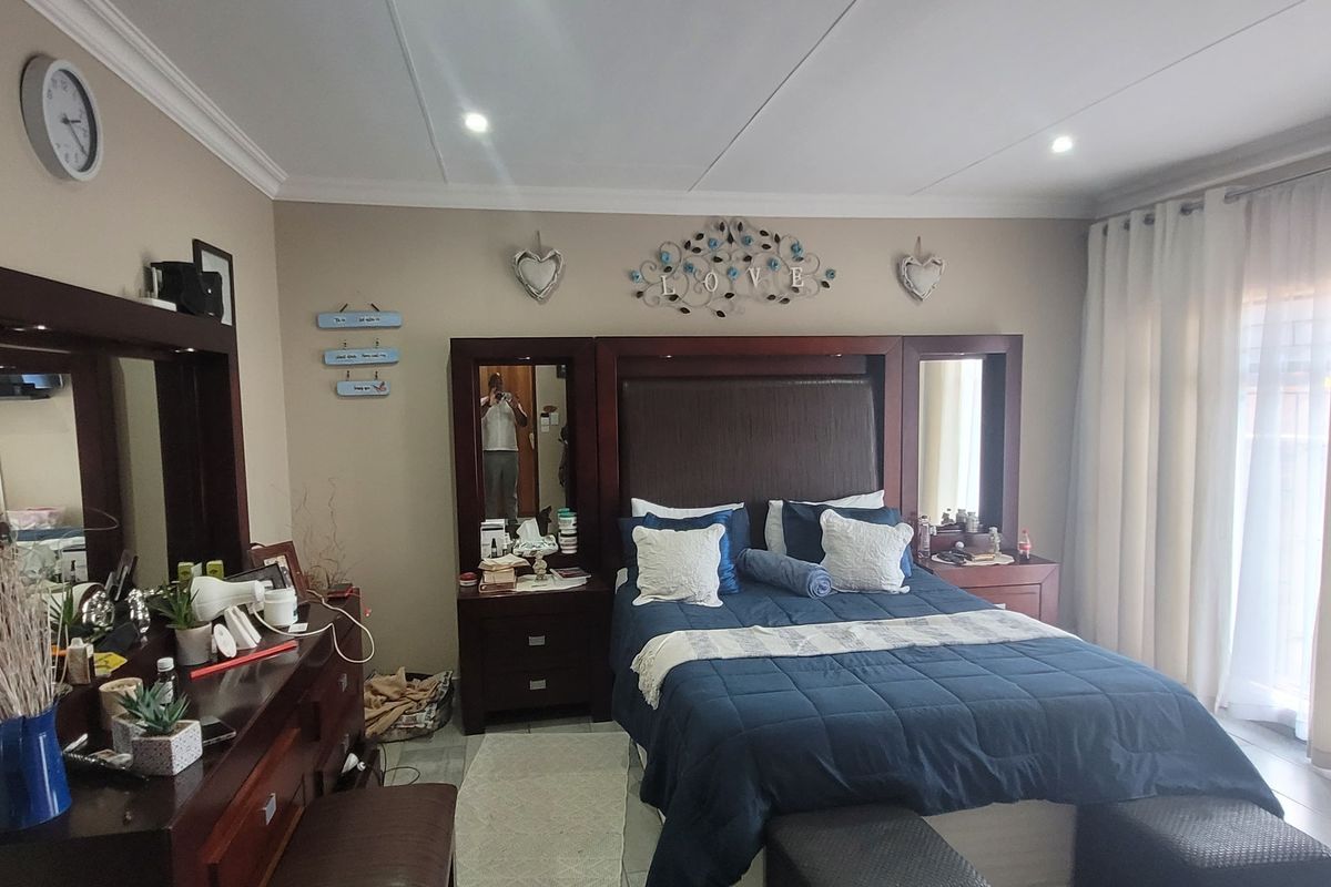 A spacious bedroom featuring tiled flooring, recessed downlighting, and a large sliding glass door providing access to the exterior.