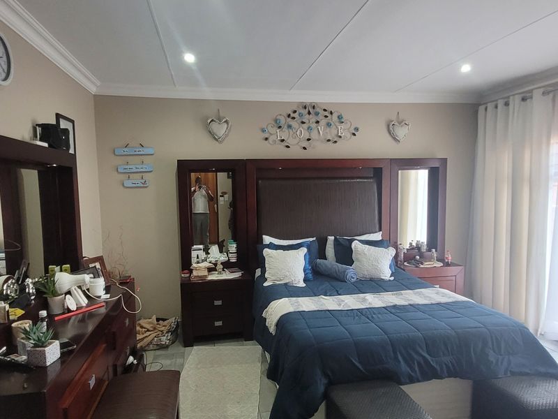 A spacious bedroom featuring tiled flooring, recessed downlighting, and a large sliding glass door providing access to the exterior.