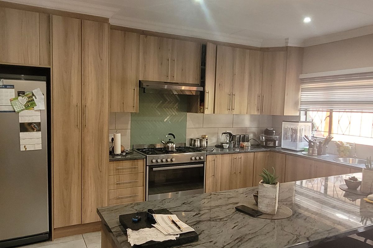 Modern kitchen featuring wood-finish cabinetry, stone countertops, a central island, and a gas stove with an integrated extractor fan.