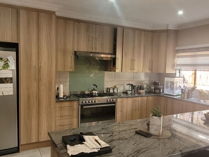 Modern kitchen featuring wood-finish cabinetry, stone countertops, a central island, and a gas stove with an integrated extractor fan.