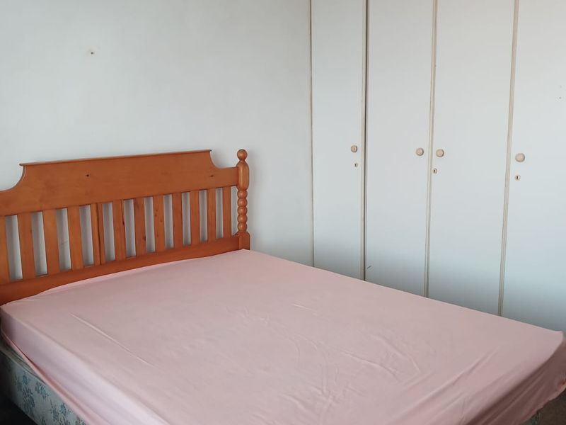 A bedroom featuring built-in white cupboards providing ample storage space.