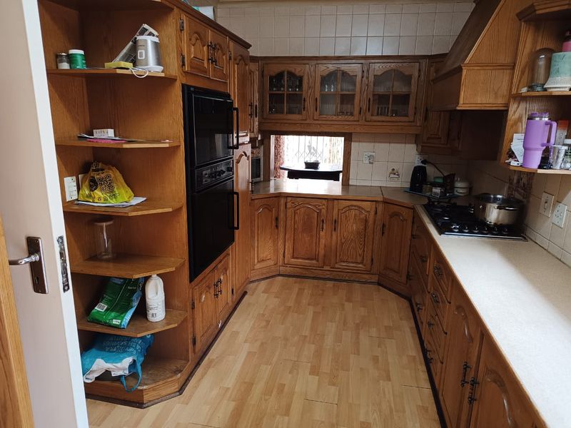 A functional kitchen featuring traditional wooden cabinetry, a built-in oven, gas hob, and tiled backsplash, offering a classic layout with ample storage space.