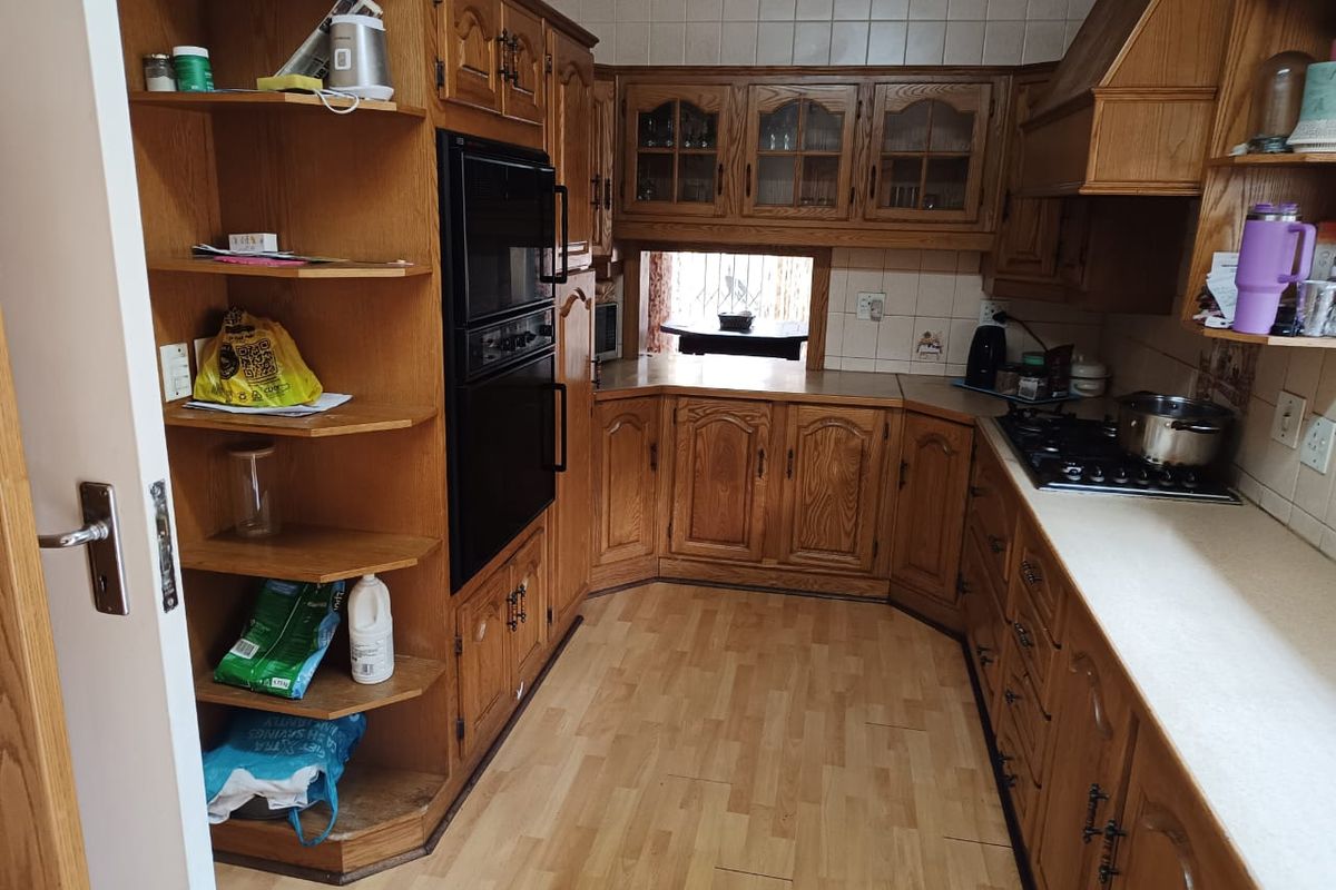 A traditional kitchen featuring extensive wooden cabinetry, built-in oven, gas hob, and tiled backsplash, offering a functional layout with ample storage space.