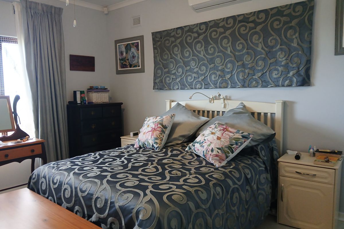 A well-maintained bedroom featuring tiled flooring, coving, and a wall-mounted split-system air conditioner.