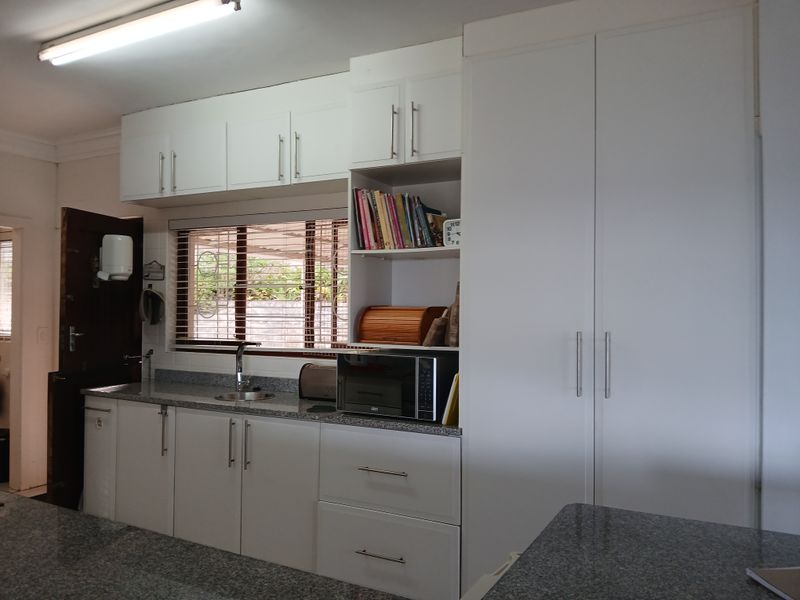 A functional kitchen featuring white cabinetry, granite countertops, and a stainless steel sink, providing ample storage and workspace.