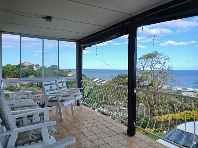 Covered balcony featuring tiled flooring, metal balustrade, and sliding glass doors, offering expansive ocean views.
