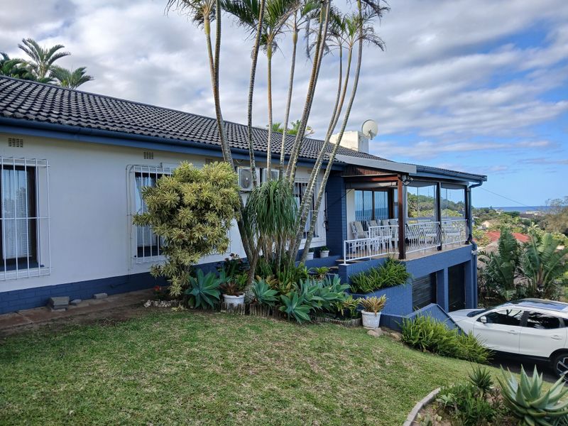 Rear elevation of the house featuring a covered patio with wrought iron railings, established garden, and integrated garage space.