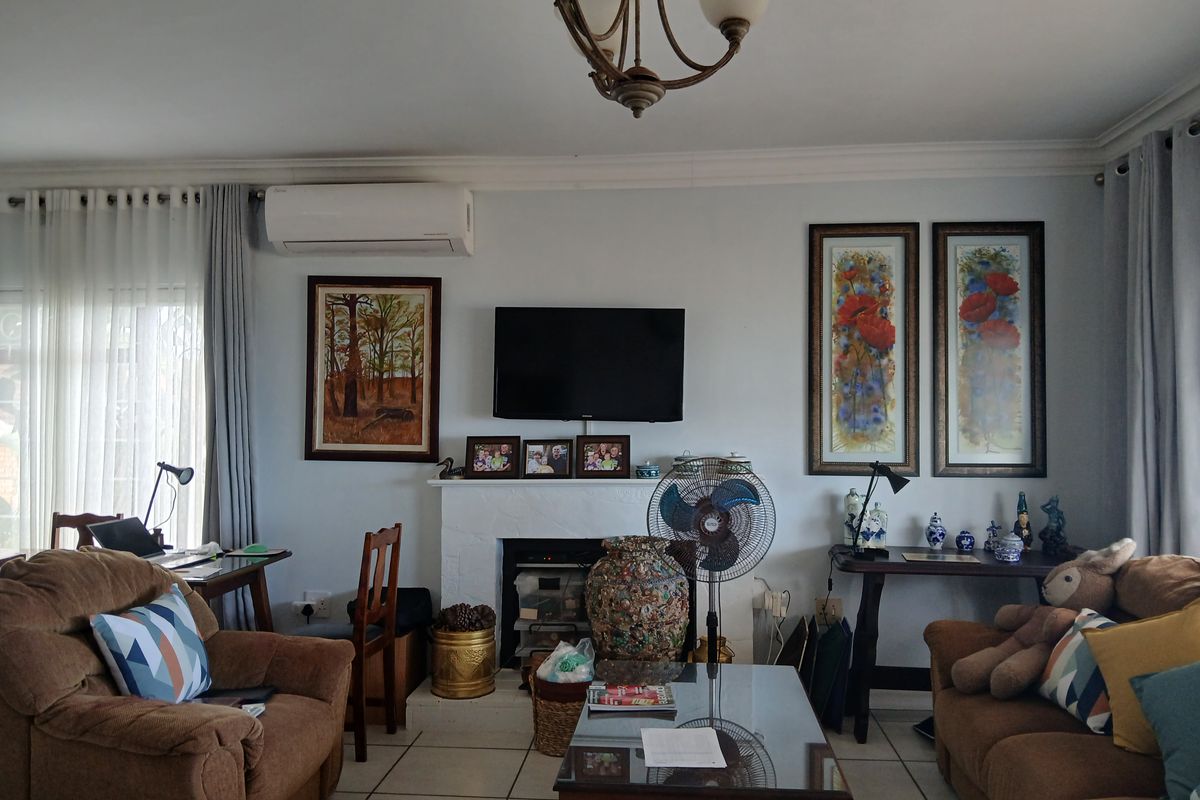A comfortable living room featuring a fireplace, tiled flooring, and a wall-mounted air conditioning unit.