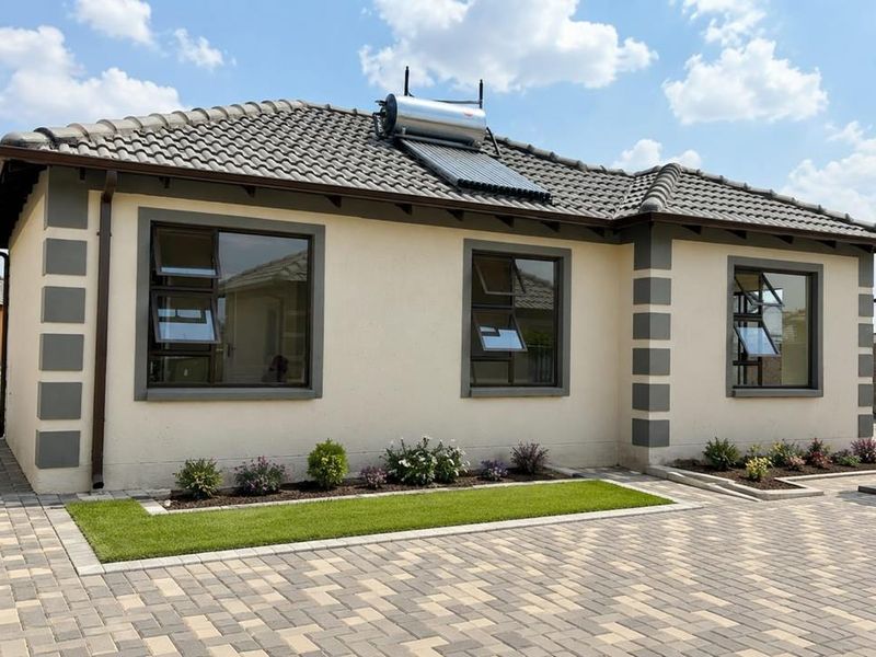 A well-maintained single-story residential property featuring a paved driveway, modern aluminium window frames, and a roof-mounted solar water heating system.