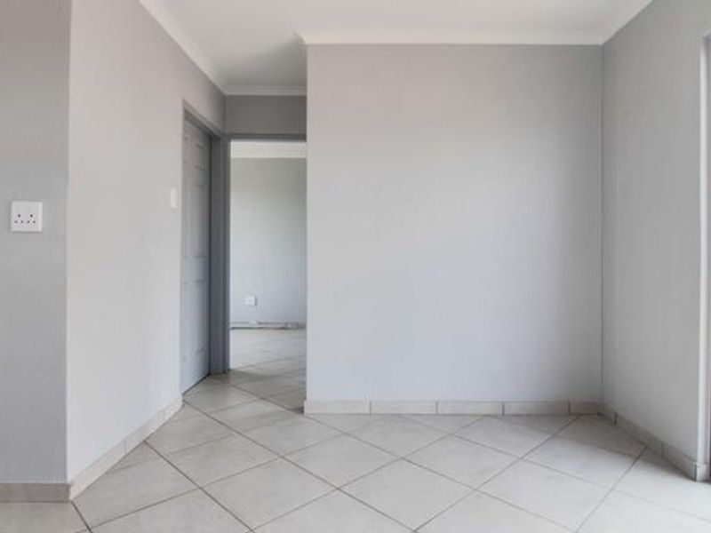 A clean, neutral-toned hallway featuring tiled flooring and access to adjacent rooms, presenting a well-maintained and versatile transition space.