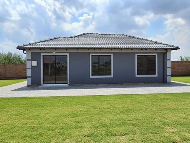 Rear view of a modern single-story house featuring a tiled roof, grey exterior walls, sliding glass doors, and a well-maintained lawn with paved patio.