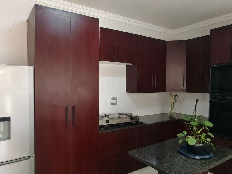 A functional kitchen featuring dark wood cabinetry, granite countertops, a built-in oven, and a gas hob with a tiled backsplash.