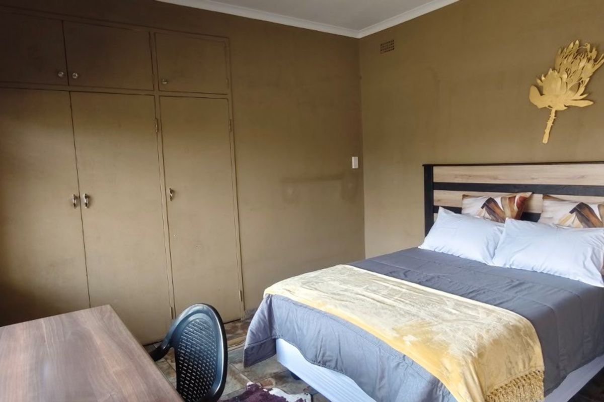 A bedroom featuring built-in cupboards, tiled flooring, and venetian blinds, offering a functional space with potential for cosmetic updates.