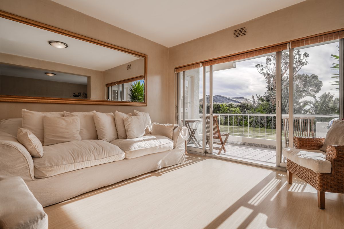 Bright living room featuring laminate flooring and large sliding glass doors that open onto a private balcony with garden views.